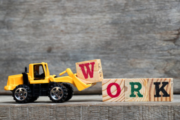 Wall Mural - Yellow plastic bulldozer hold letter w to complete word work on wood background