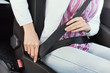 Woman fastening the seatbelt in her car