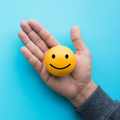 Mele hand holding yellow  emoticon ball on blue color