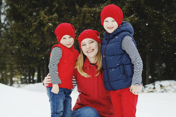 Mother and her two sons having fun in winter in snow forest