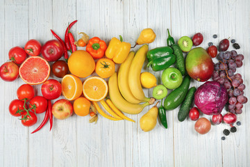 Creative composition made of fruits and vegetables in rainbow colors on wooden background, flat lay