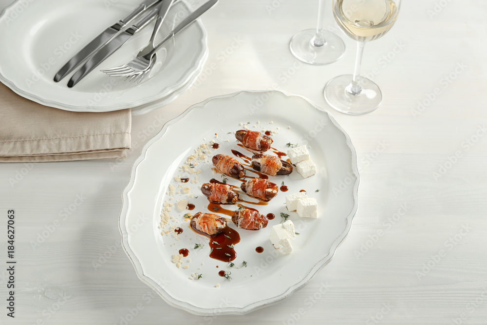 Plate with bacon wrapped dates on table