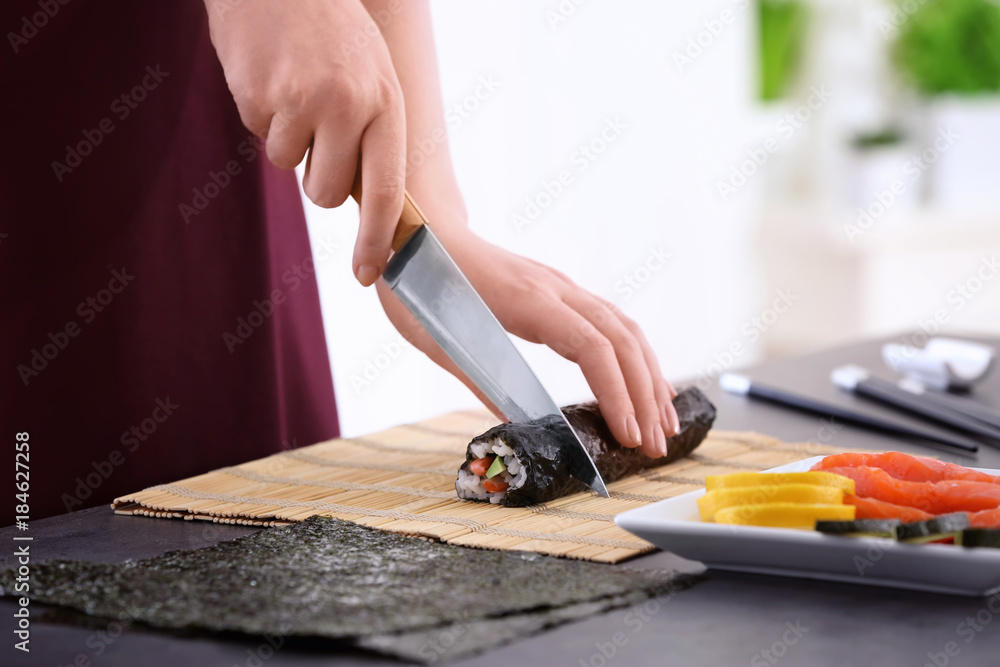 Young woman making sushi rolls at home
