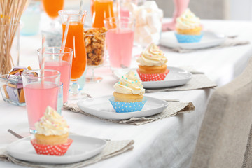 Plates with tasty cupcakes on table