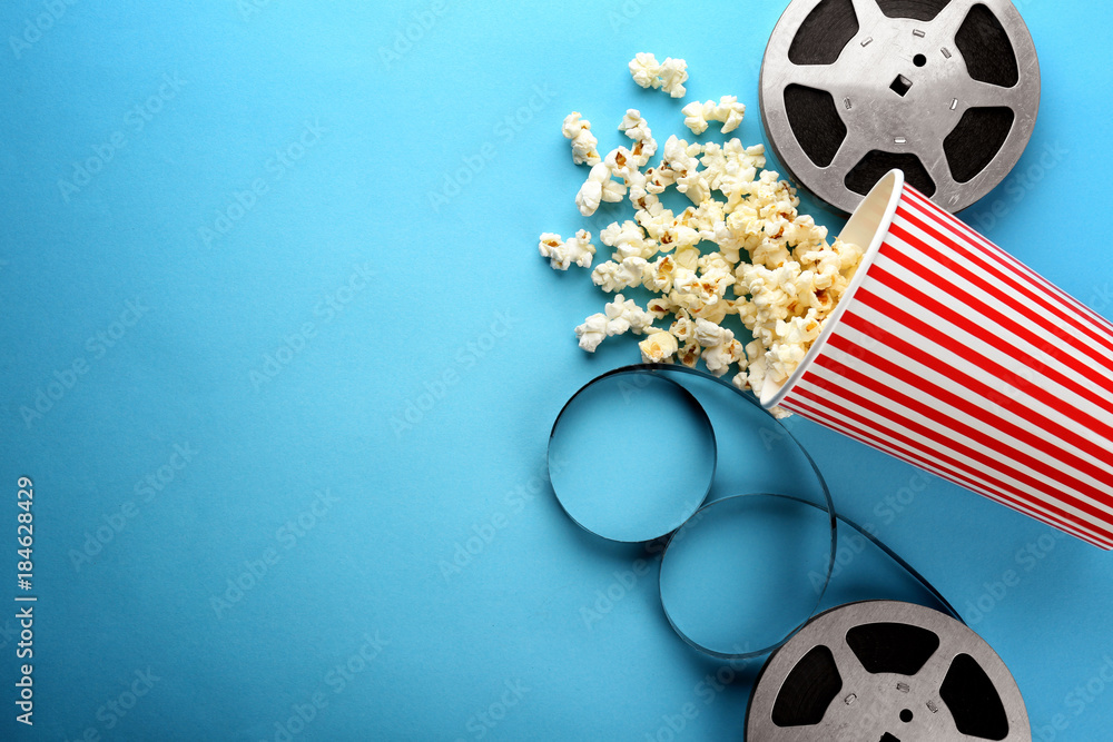 Composition with popcorn and cinema film on color background - obrazy, fototapety, plakaty 