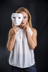 Attractive woman holding theatre mask against black background in studio