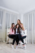 © AS Photo Family - Four cute friends girls wear on warm sweaters and black pants against old piano with christmas decoration at white room.