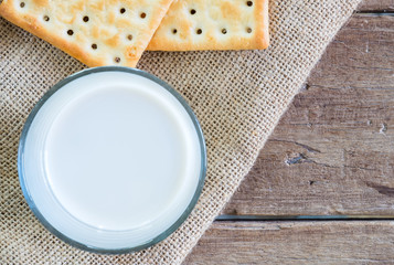 Wall Mural - stack of crackers on gunny sack cloth on wooden table with a cup of milk, top view, close up, copy space