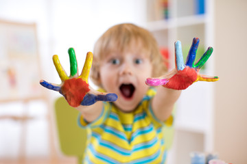 Wall Mural - Cheerful child boy showing hands painted in bright colors. Focus on color palms