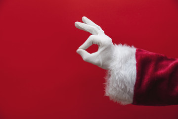 Santa Claus hand okay gesture against a red background