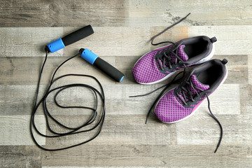 Wall Mural - Jumping rope and sneakers on wooden background