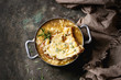 © Natasha Breen - Traditional french onion soup with cheese and bread served in vintage aluminum pan with rosemary and textile napkin over dark metal background. Top view, copy space