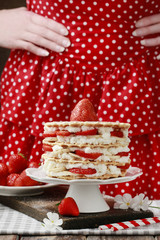 Wall Mural - Woman decorating strawberry layer cake with fresh fruits.