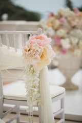 wedding decorations flowers on chairs. Wedding exit registration, white chairs decorated for wedding. wedding setup detail.