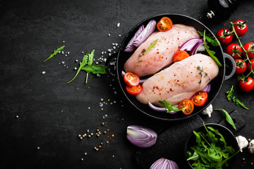 Canvas Print - Fresh raw chicken meat, fillet marinated with spices, onion and tomatoes on black background. Top view