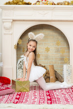 Little Girl In Fairy Pixi Costume Dress With Rabbite Ears Holds The Gift Box Under The Christmas Tree