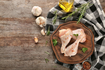 Wall Mural - Board with raw chicken legs on wooden background, top view