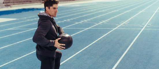 Wall Mural - athlete training with a medicine ball on running track