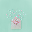 Multicolor sweets sugar candy hearts fly out of craft paper envelope on the light turquoise background . Valentine day. love concept. Gift, message for lover. Space for text. Square format.