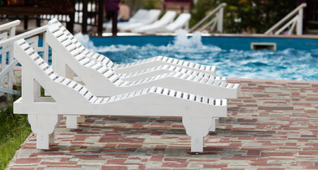  white sunbeds by the pool in the open air