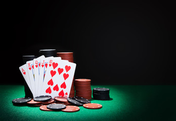 Poker winning combination royal flush with chips on green poker table. Dark background with copy space.