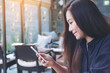 © Farknot Architect - Closeup image of a beautiful Asian woman with smiley face using and looking at smart phone in modern cafe