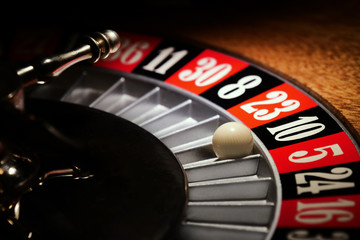 Macro shot of a roulette in a casino where the ball goes to the green or red or black number. People having bet and bet money may have won lost badges. Concept of: fate, gambling, luck, destiny.