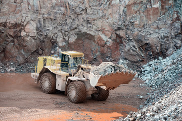 Wall Mural - Earthmover in an active quarry mine of porphyry rocks. digging.