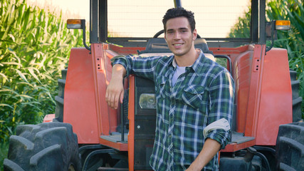 Portrait of a beautiful young farmer (student) working in the field with a tractor working in a tablet, happy, in a shirt, corn field. Concept ecology, transport, farmers, clean air, food, bio product