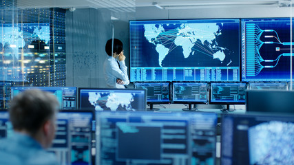 Wall Mural - In the System Control Room Chief Engineer Thinks While Standing Before Big Screen with Interactive Map on it. Data Center is Full of Monitors Showing Graphics.