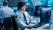 In The Security Command Center Officer At His Workstation Monitors Screens And Communicates With Patrols Through Headset. He Is Part Of The Surveillance Team.