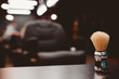 © Parilov - brush for shaving beard along with bowl, blurred background of hair salon for men, barber shop