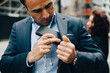 © Maskot - Mature businessman positioning mobile phone and in-ear headphones in suit pocket