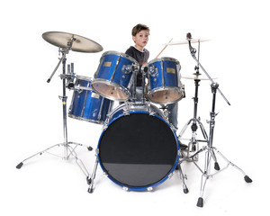 young blond boy at drum kit in studio against white background