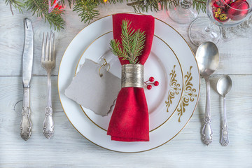 Wall Mural - table setting for christmas dinner/white plates, red napkin with vintage napkin ring, cutlery, christmas decoration on light wooden background