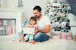 © Yarkovoy - Big father and happy little daughter open New Year's gifts near the Christmas tree