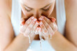 © nenetus - Beautiful young woman washing her face splashing water in a home bathroom.