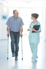 male patient with cast and surgeon walking on hospital corridor