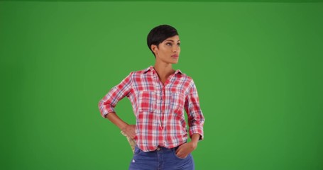 Wall Mural - Young black woman dressed in flannel shirt with hands on hips, staring at camera on green screen. On green screen to be keyed or composited. 