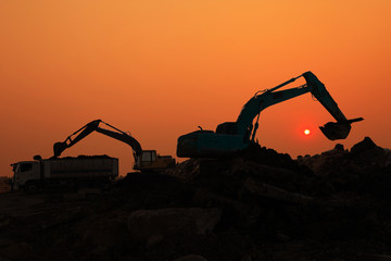 Silhouette of Excavator loader in construction site at sunset sky background