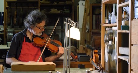 Sticker - The professional violin master makes a violin with his own hands, uses a clean tree spruce, pine, glasses, planes, tunes strings. Concept: spiritual instrument, hand made, art, music, melody, sound.