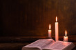 Bible and candle on a old oak wooden table.  Beautiful gold background.Religion concept.