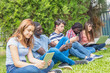 © jovannig - Teenagers of different races using tablets, smartphones and laptops in a city park