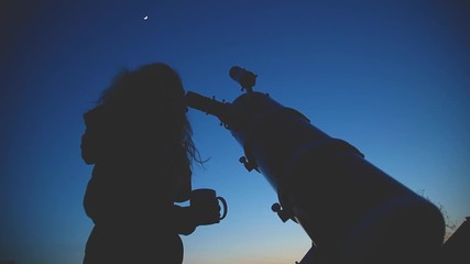 Wall Mural - silhouette of a girl while watching stars through the telescope in nature.