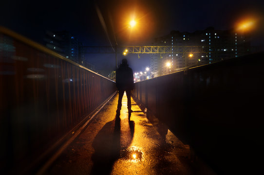 Fototapete - a mysterious man stands alone in the street, among cars in an empty city, weat road after the rain, walks the night street, dreams
