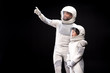 © Yakobchuk Olena - Look at this. Positive cosmonaut father is hugging his son while pointing on something while boy is feeling wonder. They are standing together wearing protective costume. Isolated with copy space