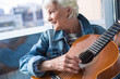 © Yakobchuk Olena - Waist up portrait of charming female pensioner playing guitar at home and smiling