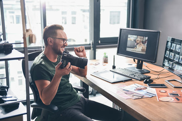 Side view smiling unshaven man looking at photo of funny dog in screen of computer while keeping camera. Work concept