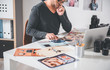 © Yakobchuk Olena - Serene bearded man watching at pictures while locating at table in room. Occupation concept