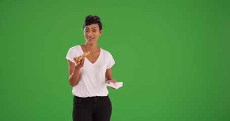 Wall Mural - Stylish black female eating a slice of delicious pizza for lunch on green screen. On green screen to be keyed or composited. 